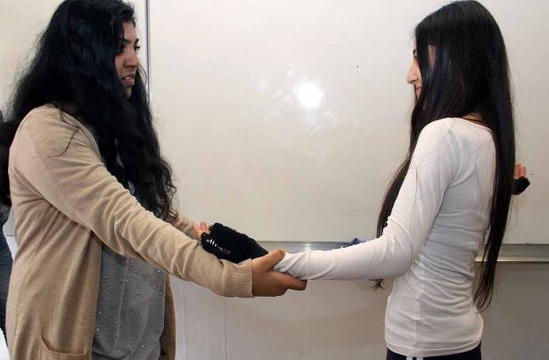 Zwei Frauen halten sich an den Händen, wobei eine eine schwarze Handschiene trägt.