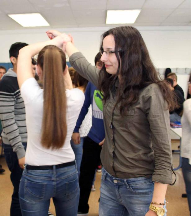 Eine Frau mit Brille führt eine andere Frau in einer Gruppe von Menschen.