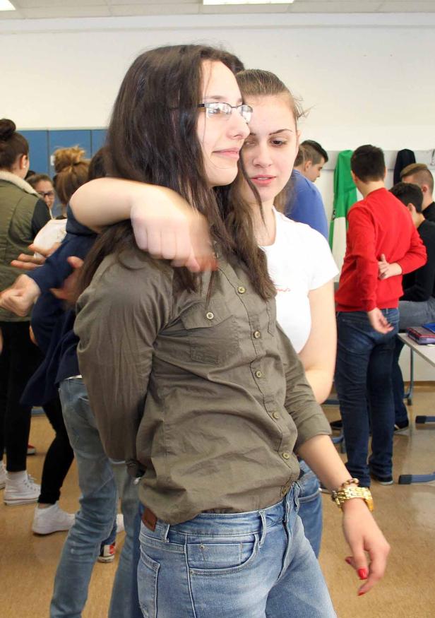 Zwei junge Frauen umarmen sich in einem Klassenzimmer.