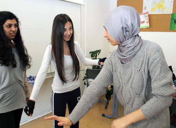 Drei junge Frauen stehen in einem Raum und unterhalten sich.