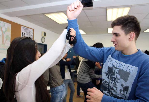 Eine Gruppe von Schülern steht zusammen und berührt sich mit erhobenen Händen.