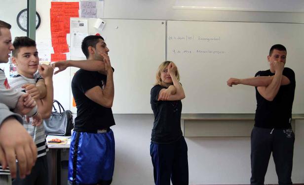 Eine Gruppe von Menschen dehnt sich vor einer Tafel in einem Raum.