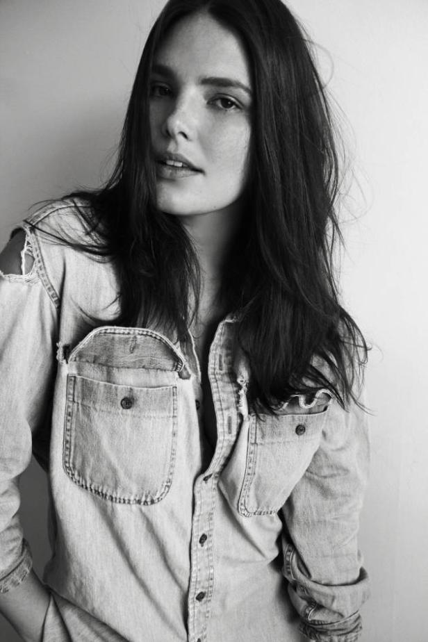 Porträt einer jungen Frau mit Sommersprossen in einem Jeanshemd.