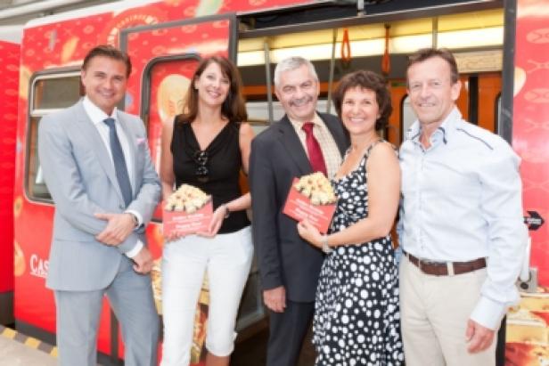 Fünf Personen posieren vor einem Zug mit roter Dekoration.