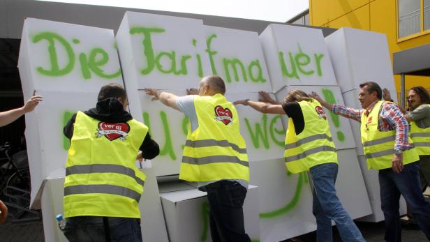 Mehrere Verdi-Mitglieder schieben eine „Tarifmauer“ aus weißen Blöcken.