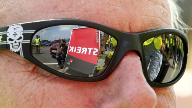Die Sonnenbrille einer Person spiegelt eine Streikdemonstration wider.