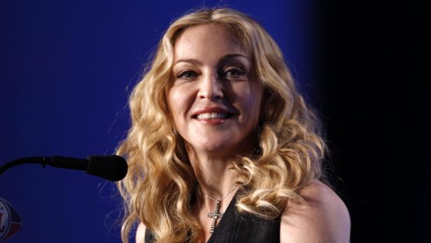 Madonna lächelt vor einem Mikrofon bei einer Veranstaltung.