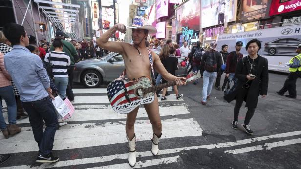 Ein Mann mit Cowboyhut und Gitarre posiert auf einem Zebrastreifen am Times Square.