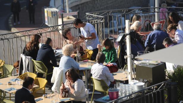 Gäste sitzen an Tischen auf der Terrasse eines Cafés.