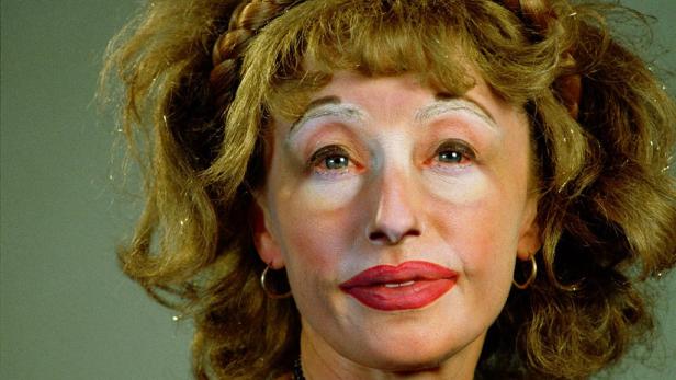 Das Porträt einer Frau mit blonden Haaren und auffälligem Make-up.