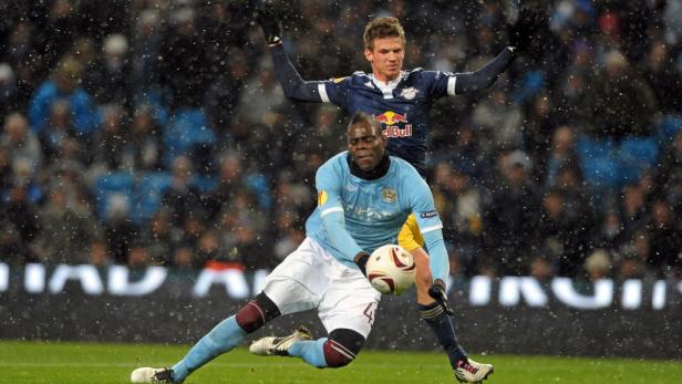 Bei Schneefall kämpfen zwei Fußballspieler um den Ball.