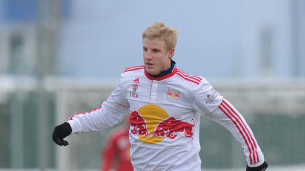 Ein junger Mann im Trikot von Red Bull Salzburg auf einem Fußballfeld.