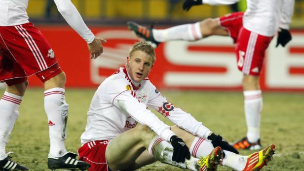 Ein Fußballspieler sitzt erschöpft auf dem Rasen.