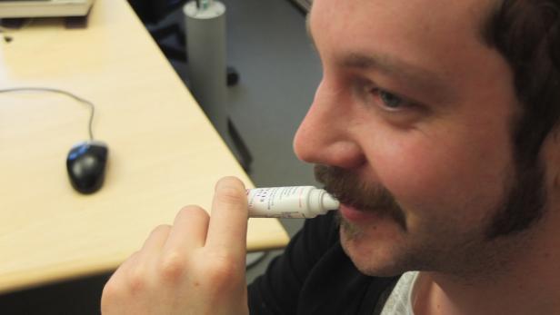 Ein Mann mit Schnurrbart trägt Lippenbalsam auf.