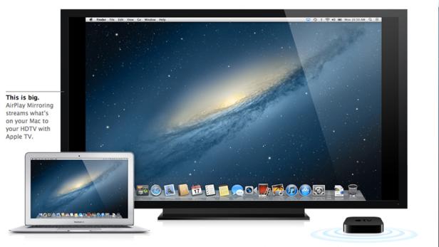 Ein Apple MacBook und ein großer Bildschirm spiegeln den gleichen Hintergrund mit einer Galaxie wider. Ein Apple TV steht rechts.