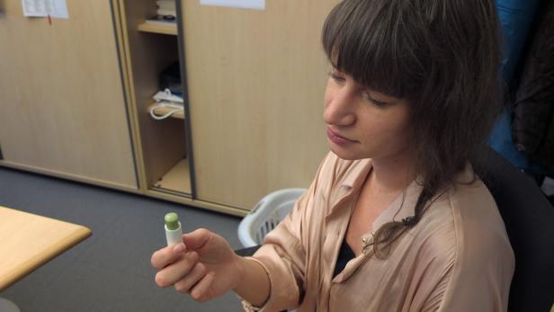 Eine Frau betrachtet einen Lippenpflegestift in ihrer Hand.