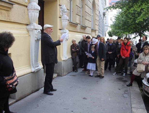 Ein Mann liest einer Gruppe von Menschen vor einem Gebäude vor.