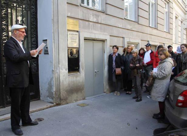 Ein Mann liest einer Gruppe von Menschen vor einem Gebäude vor.