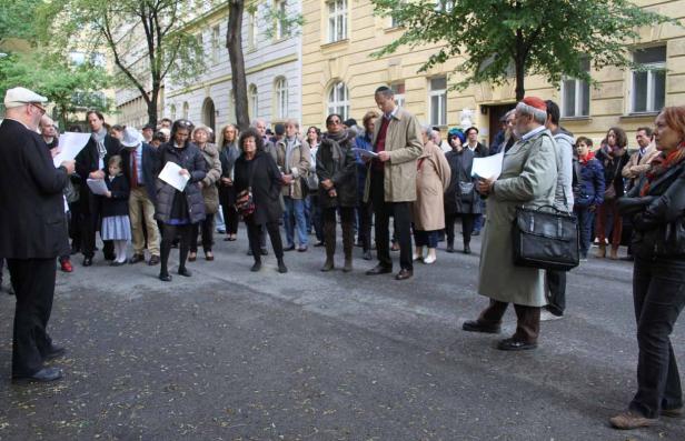 Eine Gruppe von Menschen steht auf einer Straße und liest aus Papierdokumenten.