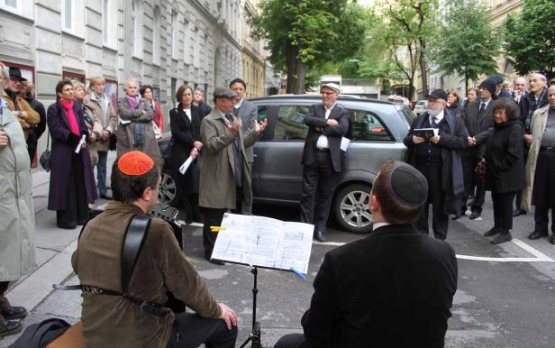 Eine Gruppe von Menschen steht um zwei Musiker mit Kippas auf einer Straße.