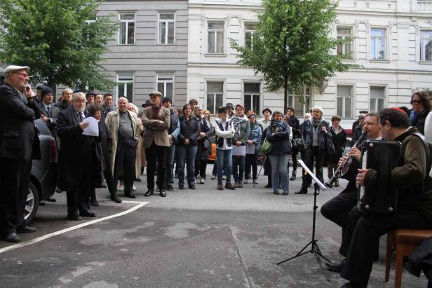 Eine Gruppe von Menschen steht auf der Straße, während zwei Musiker spielen.