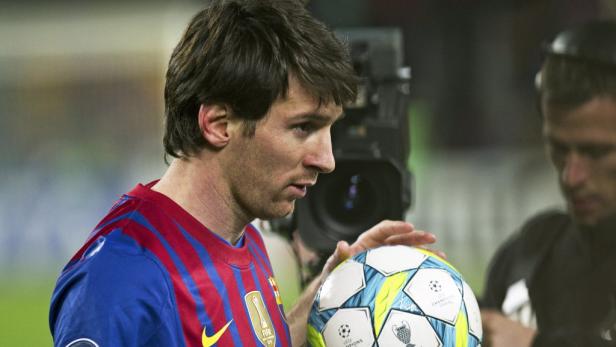 Lionel Messi hält einen Fußball der Champions League.