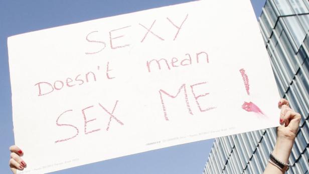 Eine Person hält ein Schild mit der Aufschrift „Sexy doesn't mean Sex ME!".