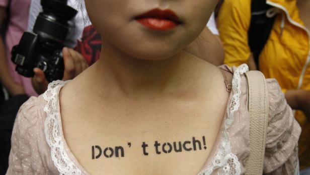 Eine Frau hat „Don't touch!“ auf ihren Oberkörper geschrieben.