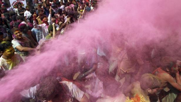 Eine Menschenmenge feiert das Holi-Fest mit rosa Farbpulver.
