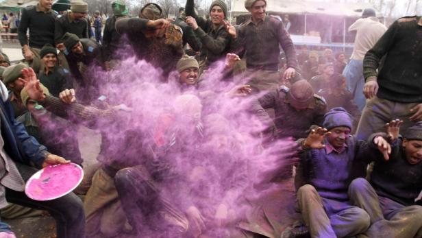 Eine Gruppe von Menschen feiert mit lila Farbpulver, möglicherweise während des Holi-Festivals.