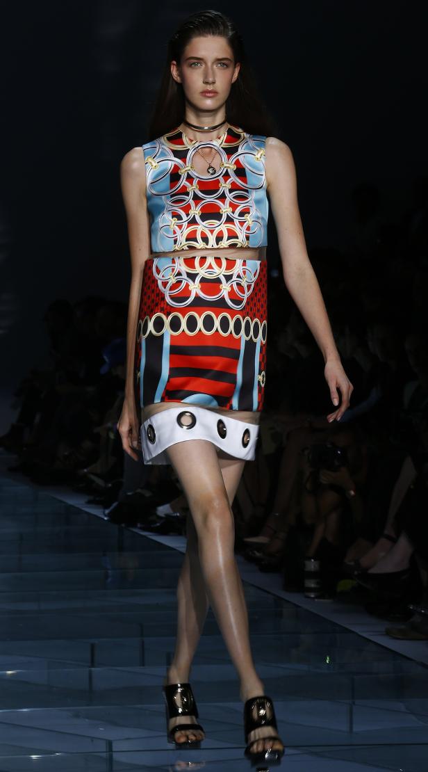 Ein Model präsentiert ein farbenfrohes Kleid mit Kreismuster auf dem Laufsteg.