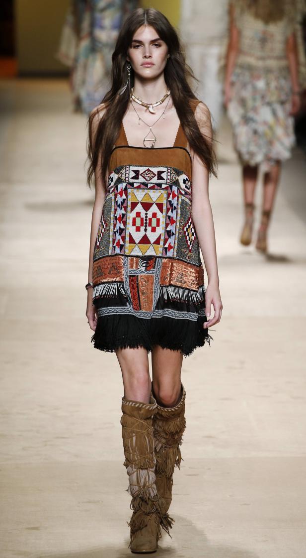 Ein Model präsentiert ein Kleid mit ethnischen Mustern und Fransenstiefel auf dem Laufsteg.