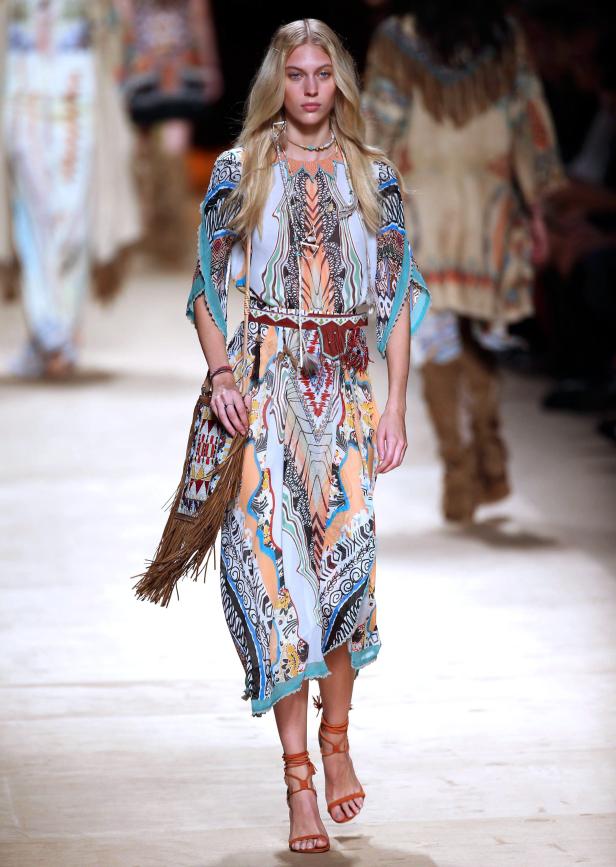 Ein Model präsentiert ein gemustertes Kleid mit Fransen auf dem Laufsteg.