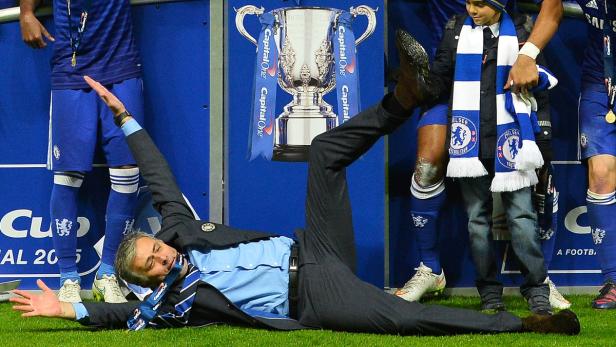 José Mourinho liegt auf dem Rasen, umgeben von Chelsea-Spielern und dem Capital One Cup.