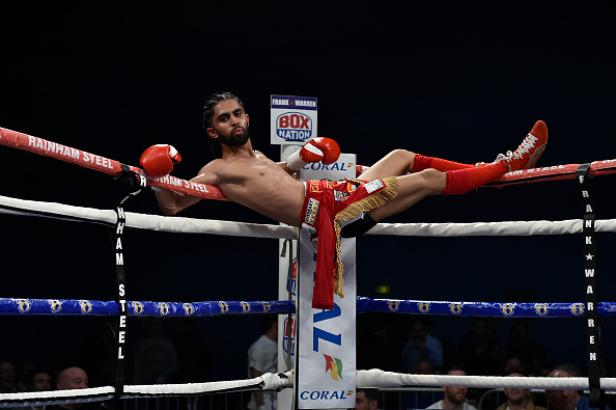 Ein Boxer liegt entspannt auf den Seilen eines Boxrings.