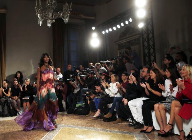 Naomi Campbell läuft in einem farbenprächtigen Kleid über den Laufsteg, während das Publikum applaudiert.