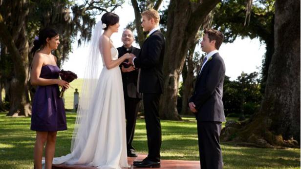 Eine Hochzeit im Freien mit Braut, Bräutigam, Priester und Brautjungfer.