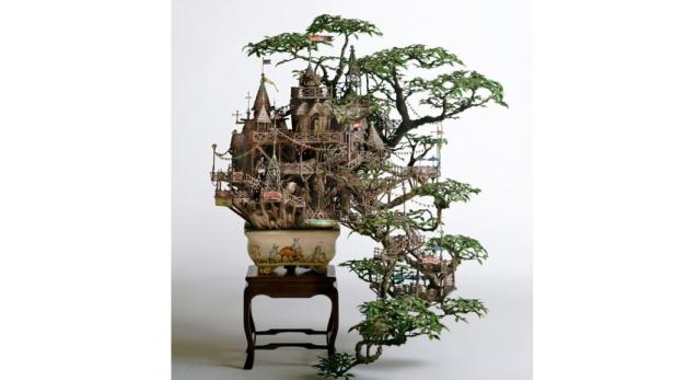 Ein Bonsai-Baum dient als Basis für ein kunstvolles, mehrstöckiges Miniaturhaus.