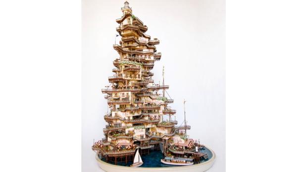 Ein detailreiches Modell eines hoch aufragenden Gebäudes mit vielen Ebenen und Booten am Wasser.