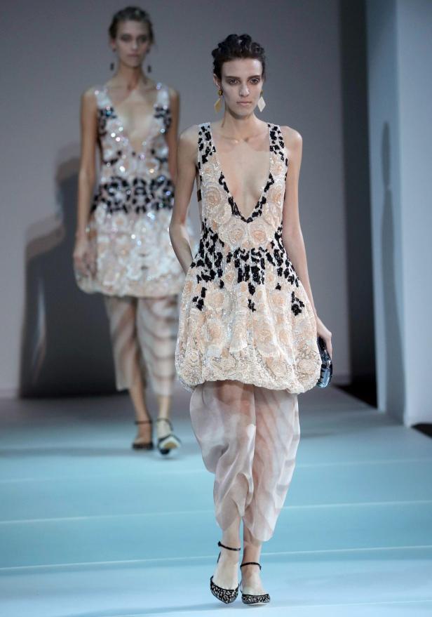 Zwei Models präsentieren Kleider mit floralen Mustern auf einem Laufsteg.