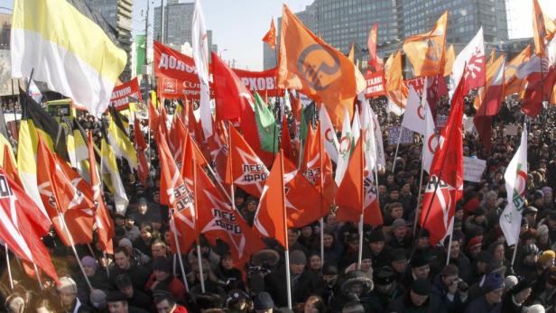 Eine Menschenmenge demonstriert mit vielen roten und einigen andersfarbigen Flaggen.
