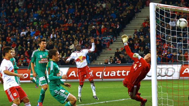 Ein Fußballspiel mit Spielern in roten und grünen Trikots vor einer Zuschauermenge.
