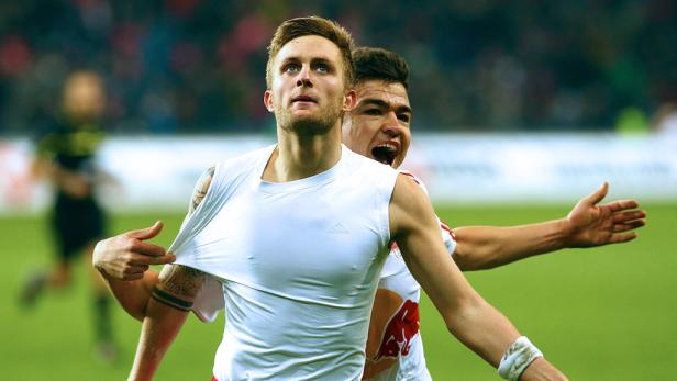Ein Fußballspieler zieht sein Trikot hoch, während ein anderer Spieler jubelt.