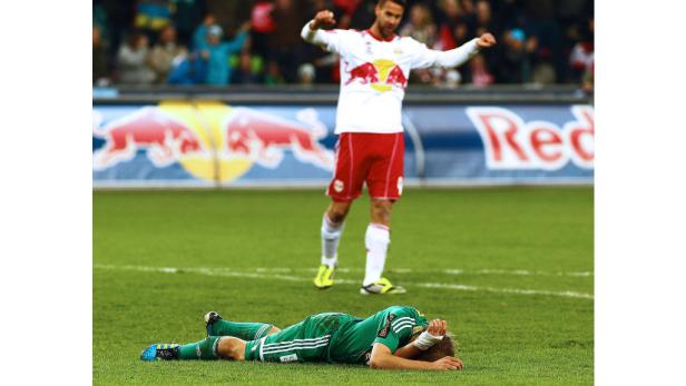 Ein Fußballspieler liegt enttäuscht auf dem Rasen, während ein anderer jubelt.