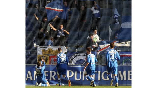 Fußballspieler jubeln vor einer jubelnden Menge im Stadion.