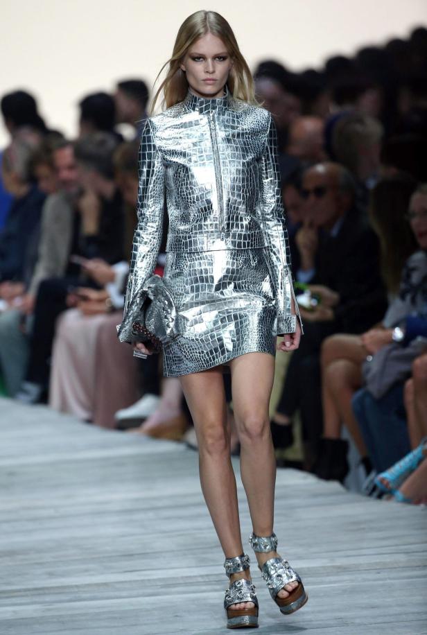 Ein Model präsentiert ein silbernes Kleid im Kroko-Look auf dem Laufsteg.