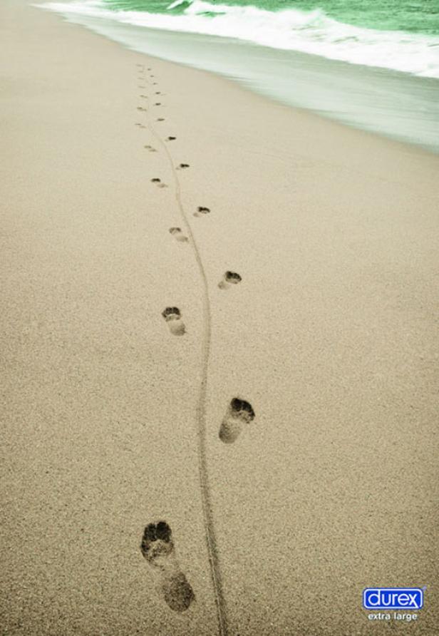 Fußspuren im Sand führen auf einen Strand zu.