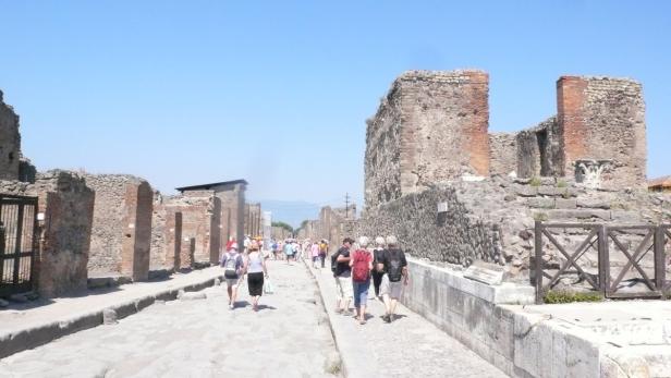 Touristen besuchen die Ruinen von Pompeji an einem sonnigen Tag.