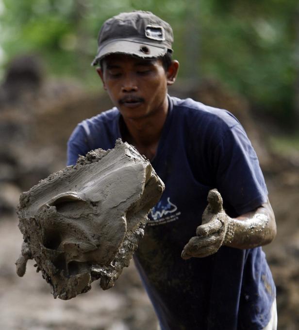 Ein Mann hält einen Klumpen Erde in seinen Händen.