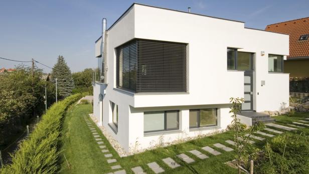 Ein modernes, weißes Haus mit einem gepflegten Garten und einem Plattenweg zum Eingang.